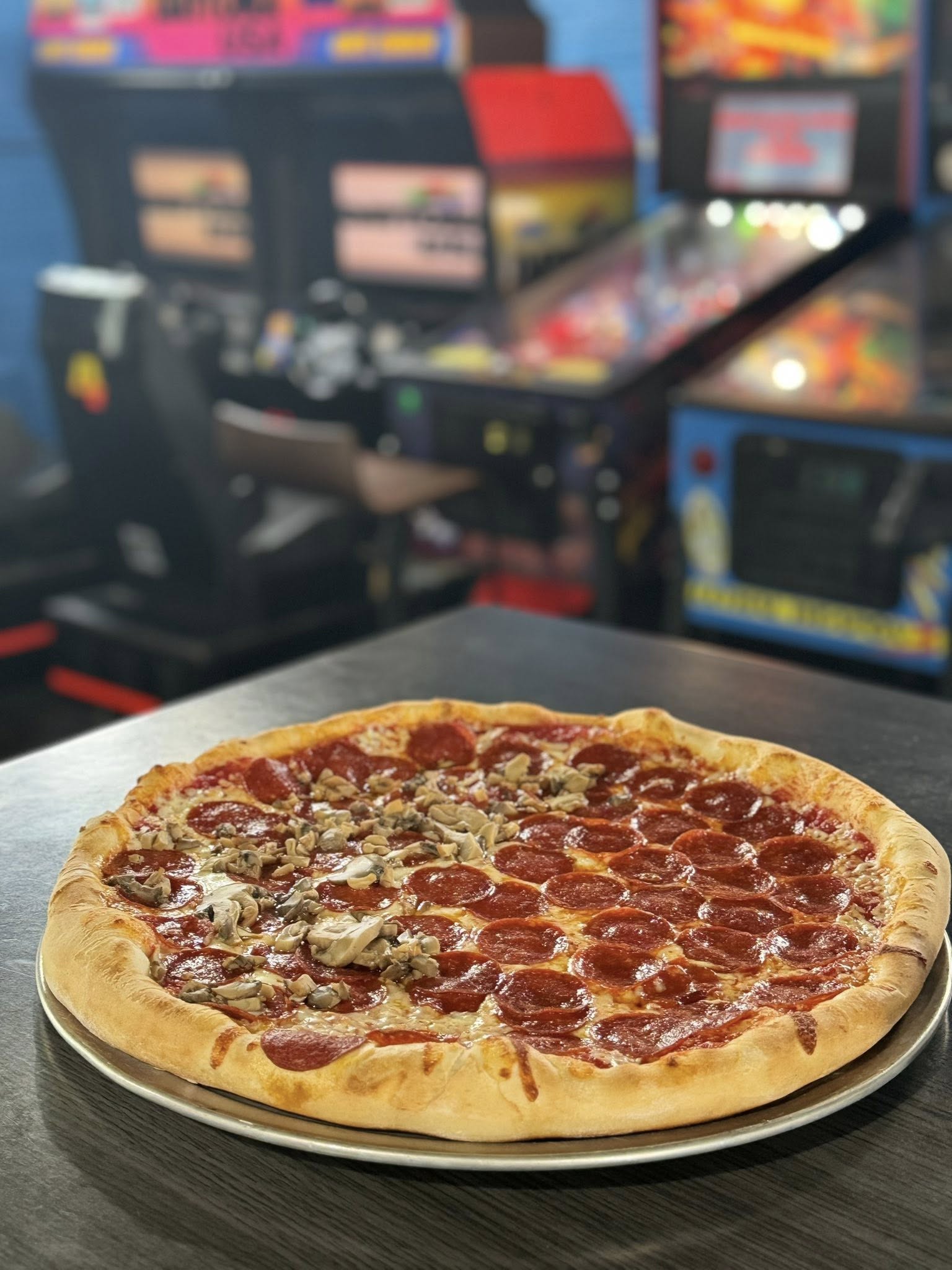 Pepperoni pizza on a tray with arcade games in the background
