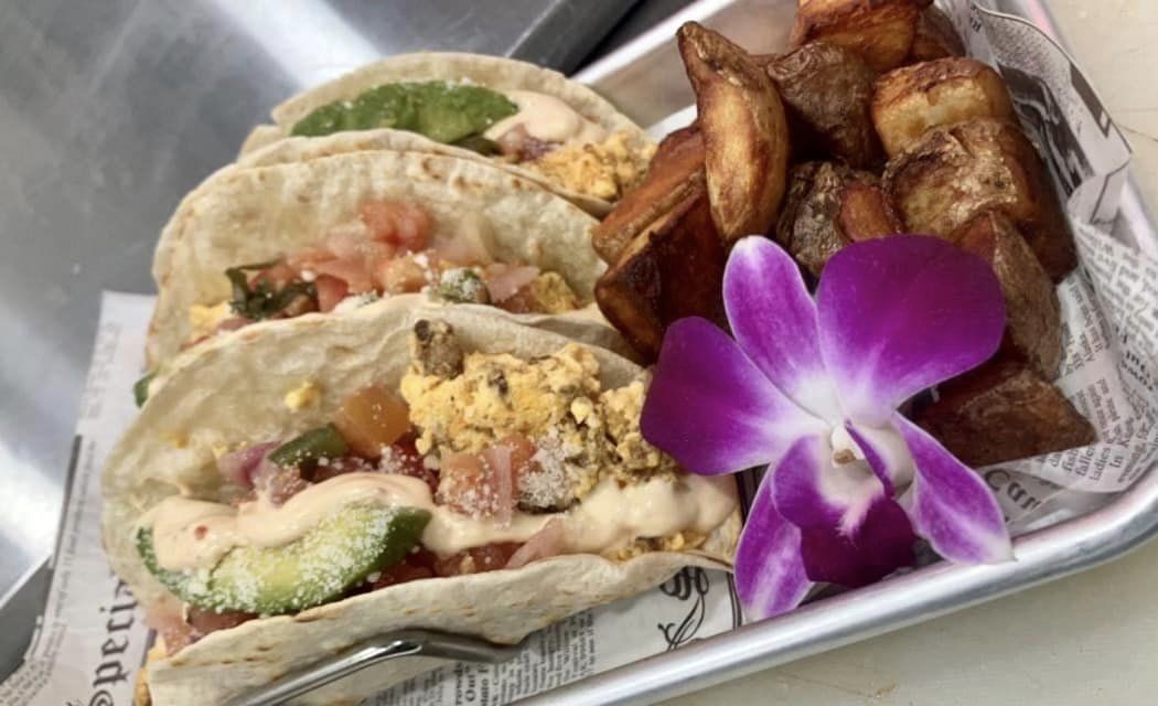 Breakfast tacos on a try with potatoes and a hibiscus flower