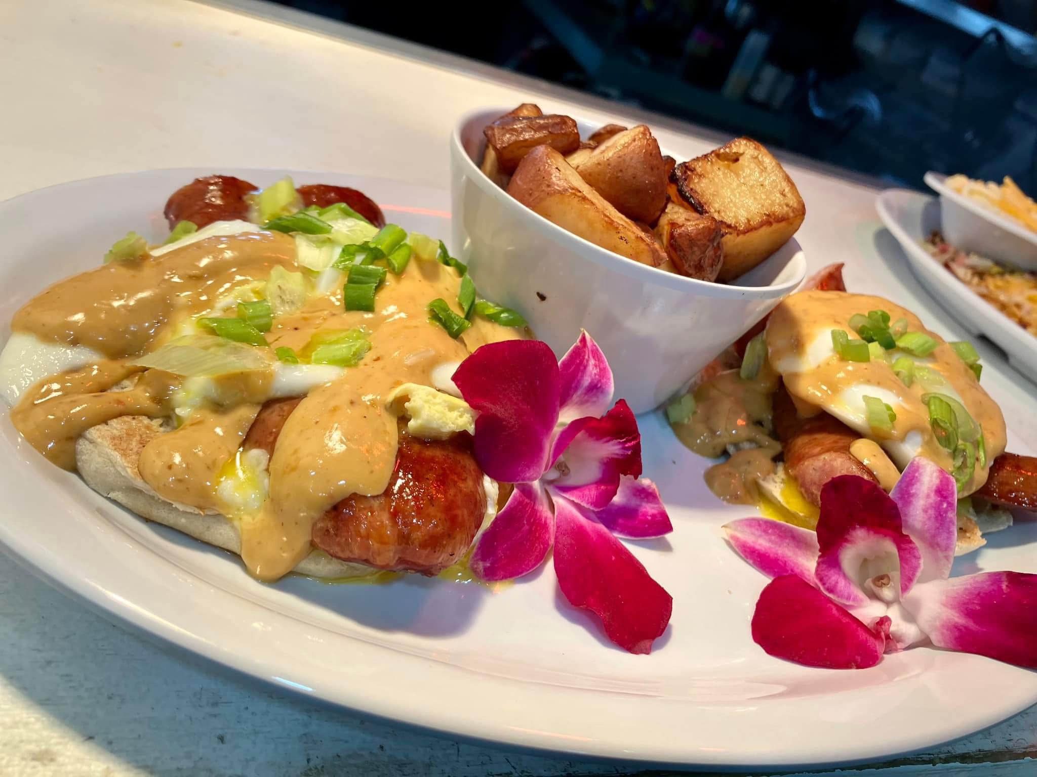 Eggs benedict plates with potatoes and hibiscus flowers for color