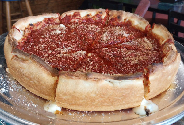 A Chicago style Stuffed pizza sliced into 8 pieces with cheese oozing.