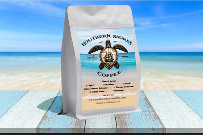 Image of a coffee bag on a wooden table with the beach in the background. 